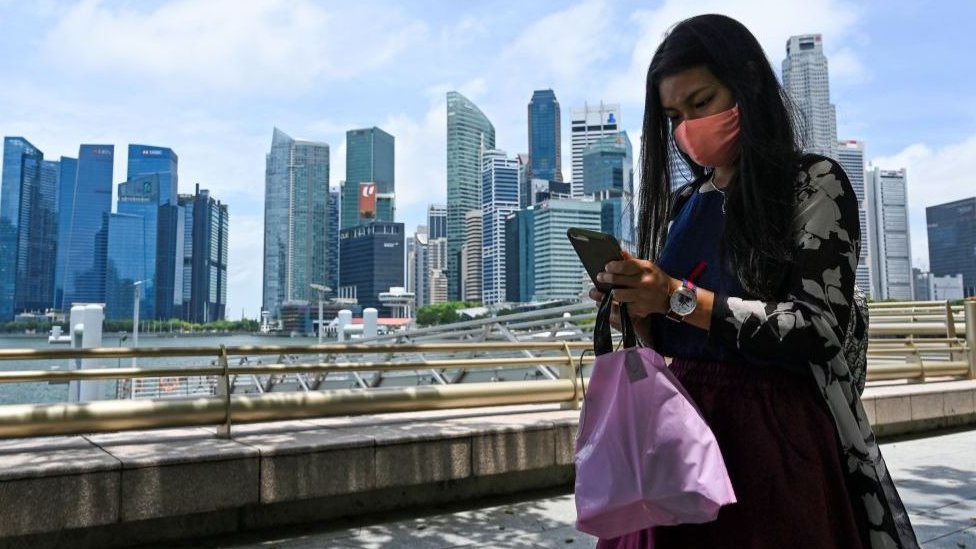 Женщина по мобильному телефону на фоне горизонта Сингапура