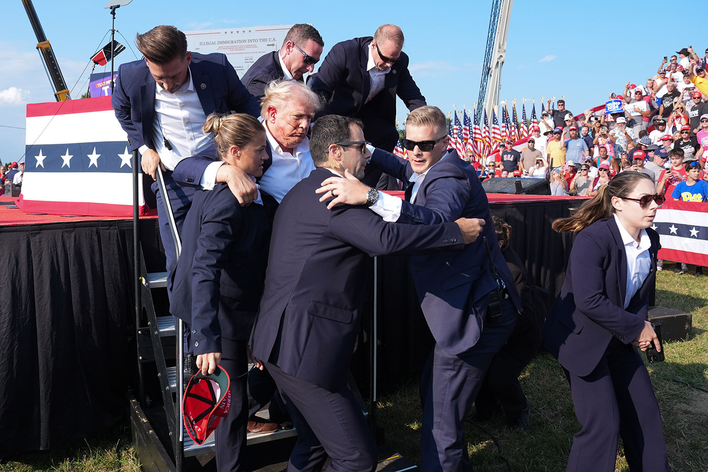 Security personnel guide Trump off stage