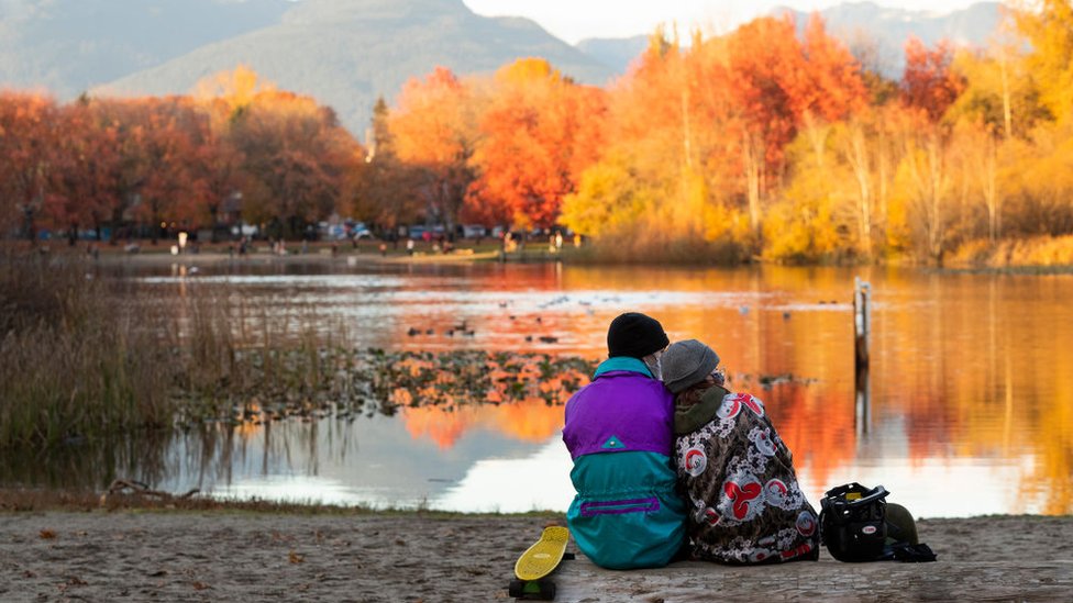Dos jóvenes sentados enfrente de un lago