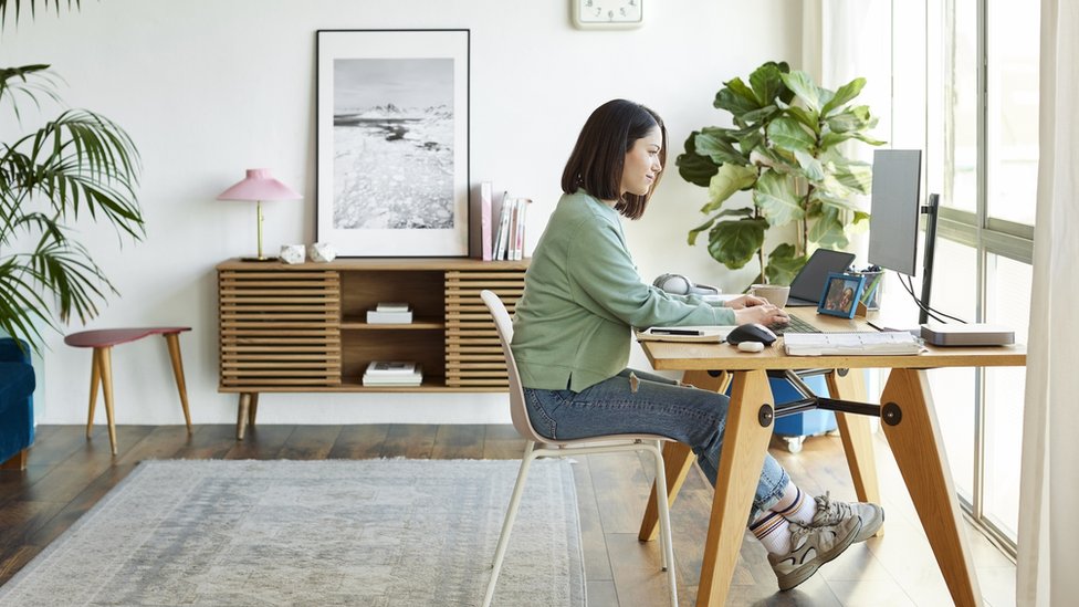 Image of a woman working from the living room of a house.
