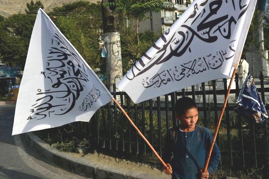 喀布爾的一名男孩拿著塔利班旗幟出售。