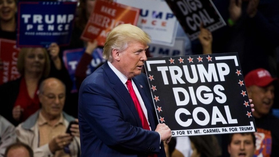 Кандидат в президенты от республиканцев Дональд Трамп держит знак в поддержку угля во время митинга на арене Mohegan Sun в Уилкс-Барре, штат Пенсильвания (10 октября 2016 г.)