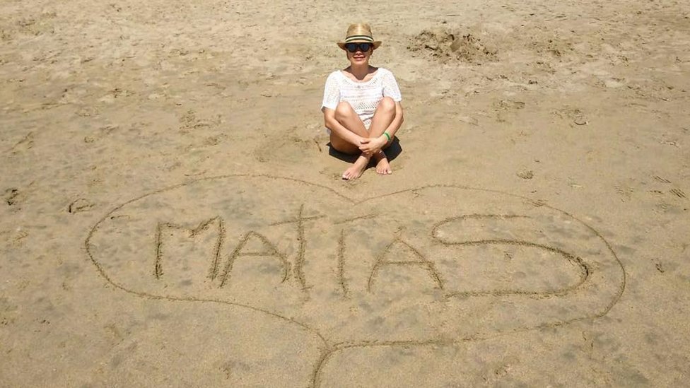 Ileana García Mora sentada en la playa frente al nombre de su hijo, Matías
