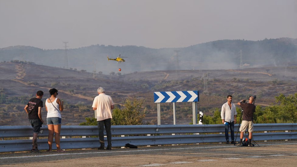 مواطنون يشاهدون جهود إطفاء حرائق الغابات في كاسيريس ، إكستريمادورا ، إسبانيا يوم الجمعة
