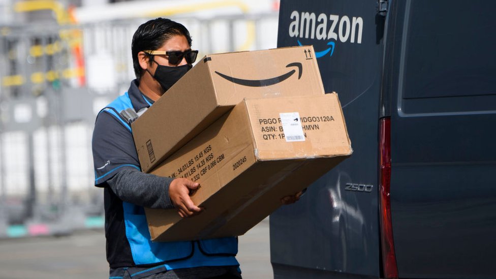 Trabajador de Amazon cargando unas cajas.