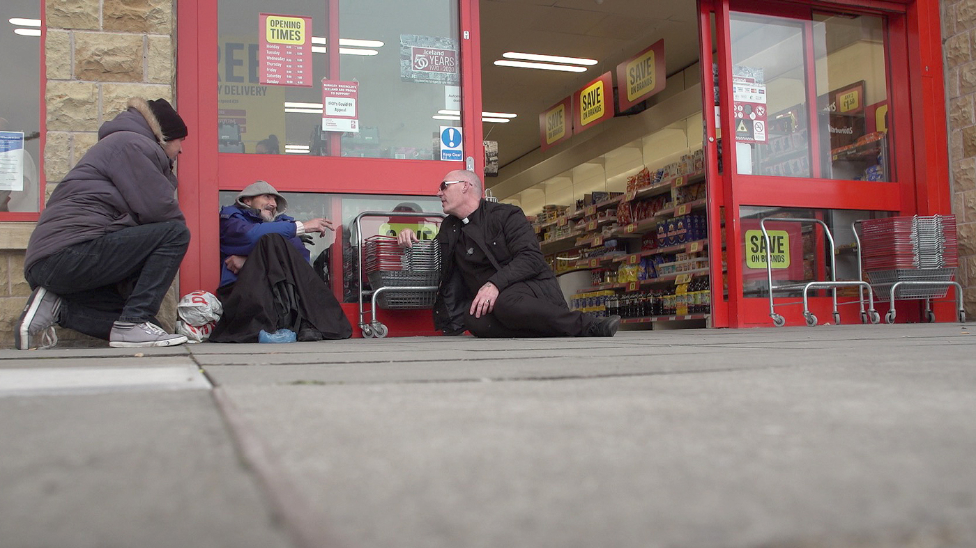 Пастор Мик Флеминг разговаривает с мужчиной на земле возле магазина
