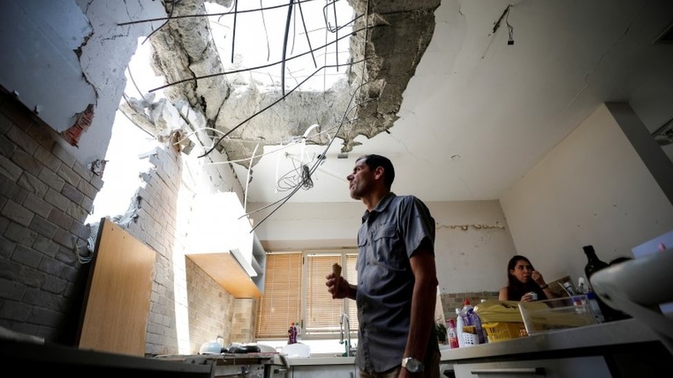Adi Vaizel, looks at the damage caused to the kitchen of his house after it was hit by a rocket launched from the Gaza Strip