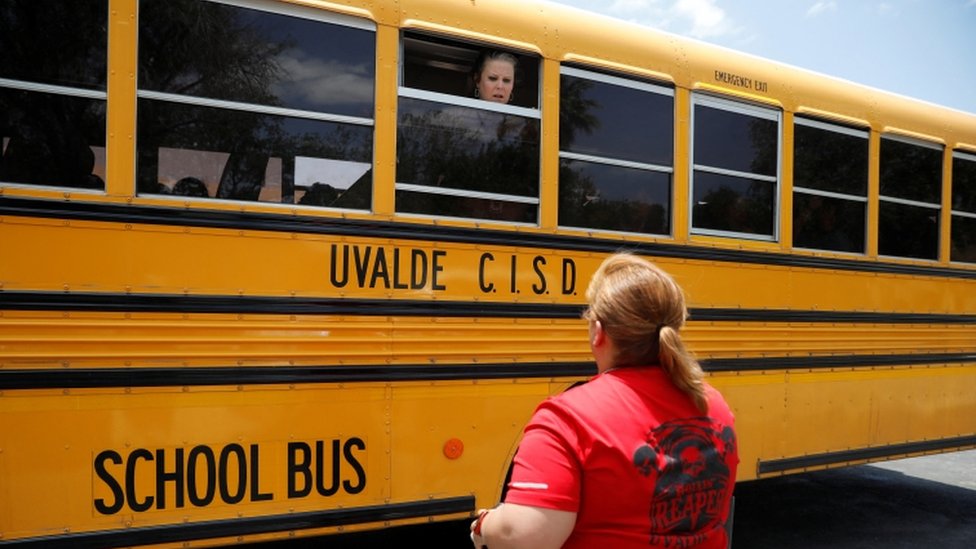 Una maestra habla con una madre desde un bus escolar en Uvalde, Texas