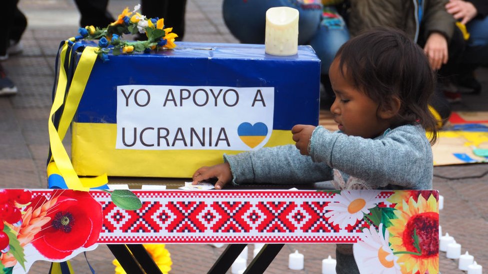 Un niño junto a una caja que recibe aportes para Ucrania en Perú.