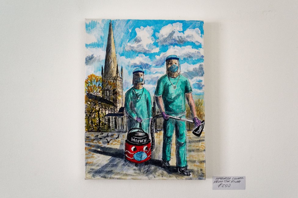 Pintura de profissionais de saúde do NHS com roupas de proteção, um aspirador de pó na mão e a Hadleigh Church ao fundo