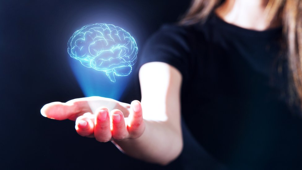 Concept image: A woman with the hologram of a brain projected on the palm of her hand