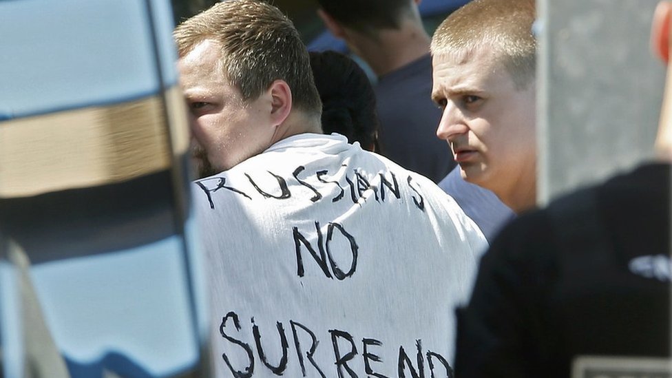 Российских футбольных болельщиков, подозреваемых в причастности к столкновениям, на одном из которых был плакат с надписью «Россия не сдаётся», выводят из автобуса