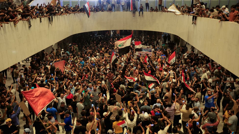 Hundreds of political protesters, some waving flags, fill Iraq's parliament building