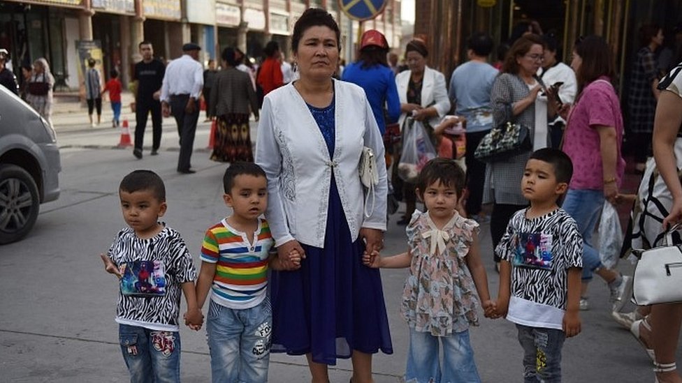 امرأة من الإيغور تنتظر مع أولادها في شارع بكشغار، شمال غرب منطقة شينغيانغ في الصين