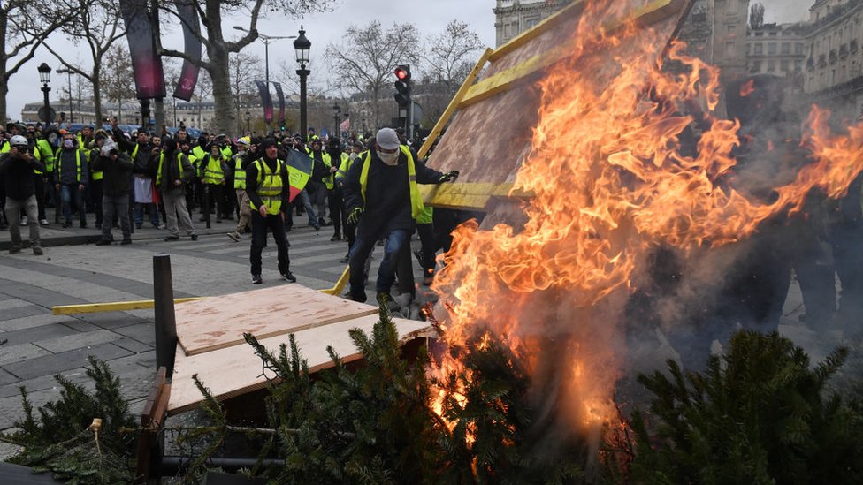 Manifestantes quemando árboles de navidad