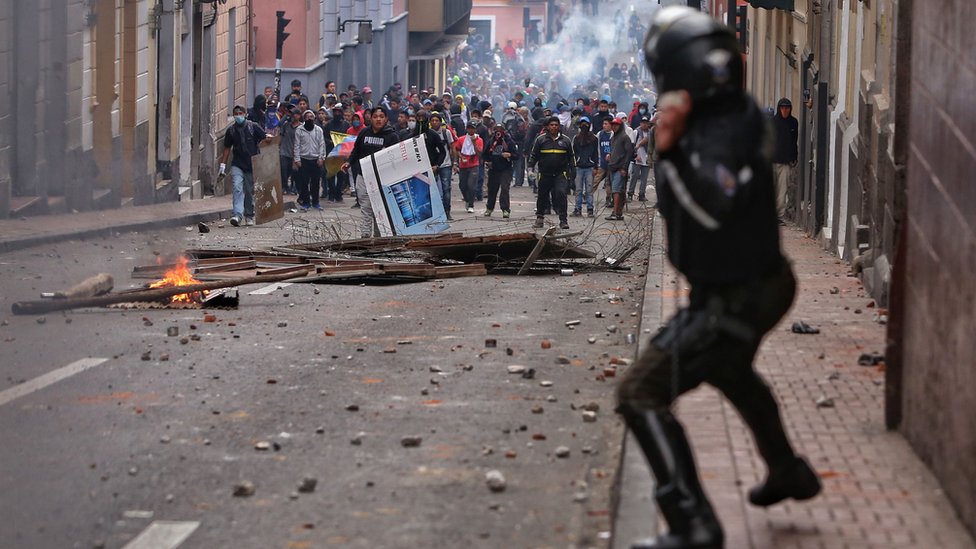 Офицер ОМОН противостоит демонстрантам во время столкновений в Кито 7 октября 2019 г.