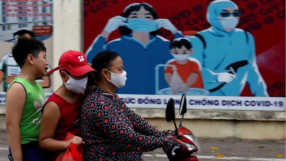 A woman wears a protective mask as she drives past a banner promoting prevention against the coronavirus disease (COVID-19) in Hanoi, Vietnam July 31, 2020.
