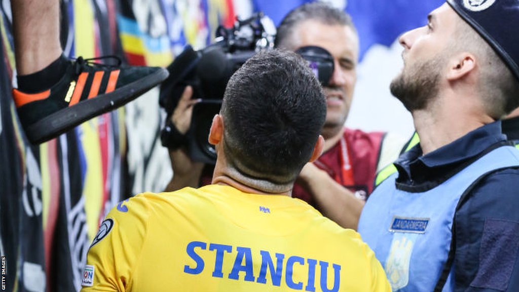 Romania midfielder Nicolae Stanciu spoke with Romanian fans after the referee stopped the match