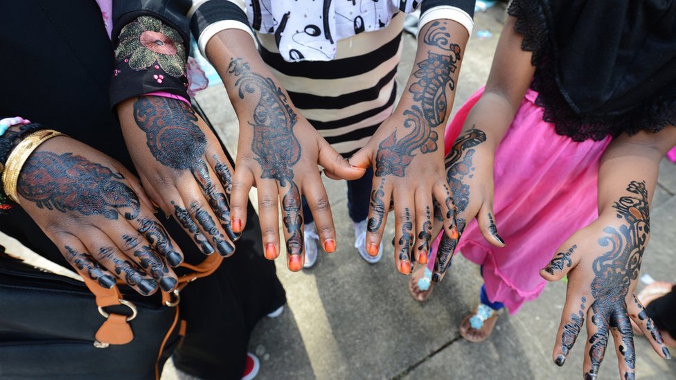 Gadis-gadis Muslim menunjukkan tangan mereka yang dihias dengan henna sepulang salat Idul Fitri.
