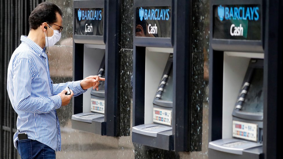 Мужчина пользуется банкоматом с закрытым лицом