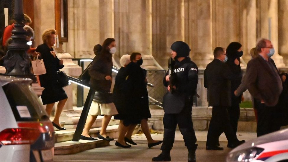 Opera guests leave the state opera under the supervision of armed policemen, in the centre of Vienna on November 2, 2020