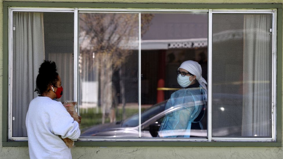 Una joven mira a una mujer a través de una ventana