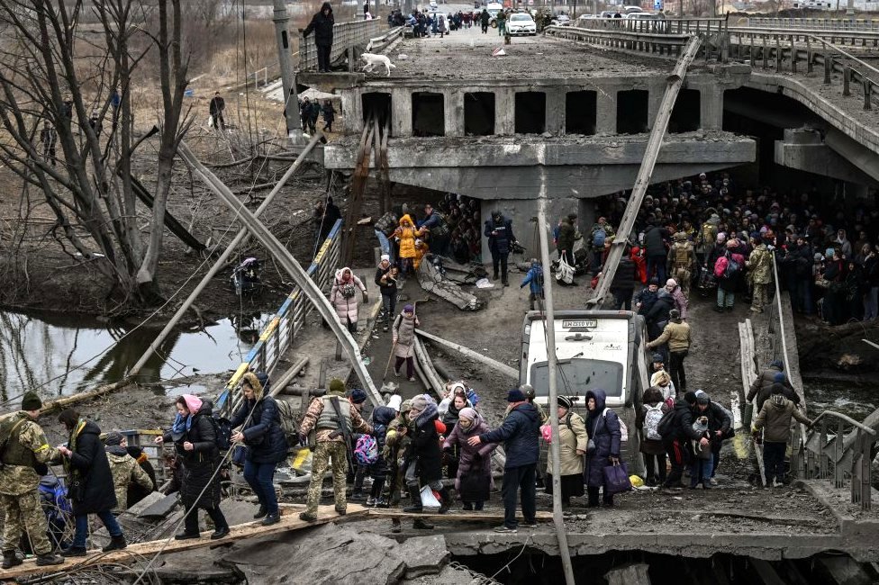 أشخاص يعبرون جسرا مدمرا أثناء إخلاء مدينة إيربين، 5 مارس/آذار 2022