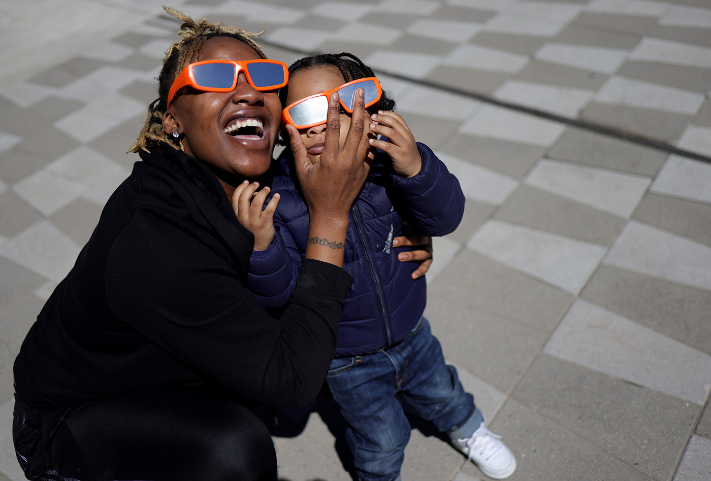 A woman and child take in the partial solar eclipse outside of the Fiserv Forum in Milwaukee, Wisconsin - 8 April 2024 (Kevin Dietsch/Getty Images)
