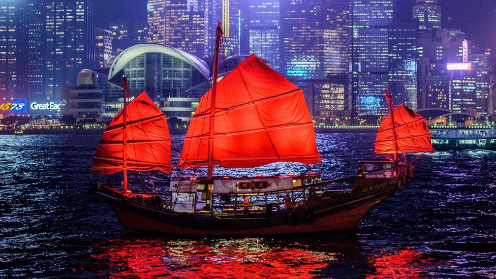 A traditional wooden tourist junk boat sails in the waters of Victoria Harbour in Hong Kong