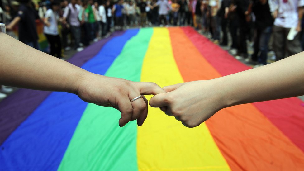 Gay and lesbian activists form a human chain around a rainbow flag during celebrations marking the fourth annual International Day Against Homophobia (IDAHO) in Hong Kong on May 18, 2008.