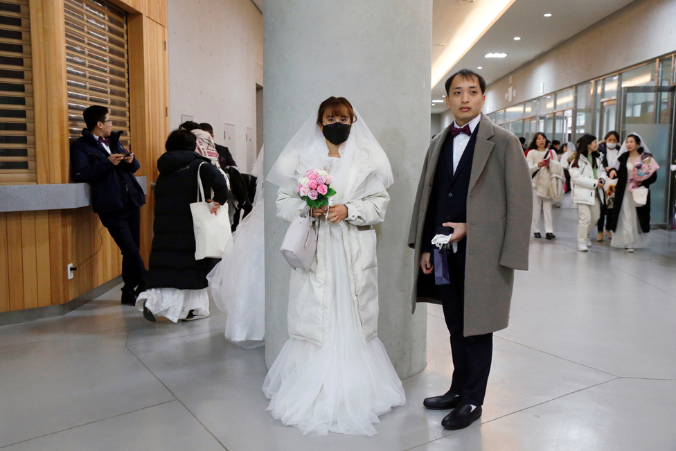 عروس ترتدي قناعاً للحماية من فيروس كورونا الجديد، تشارك في حفل زفاف جماعي أقامته الكنيسة الموحدة في مركز تشونغشيم للسلام العالمي في غابيونغ، كوريا الجنوبية.