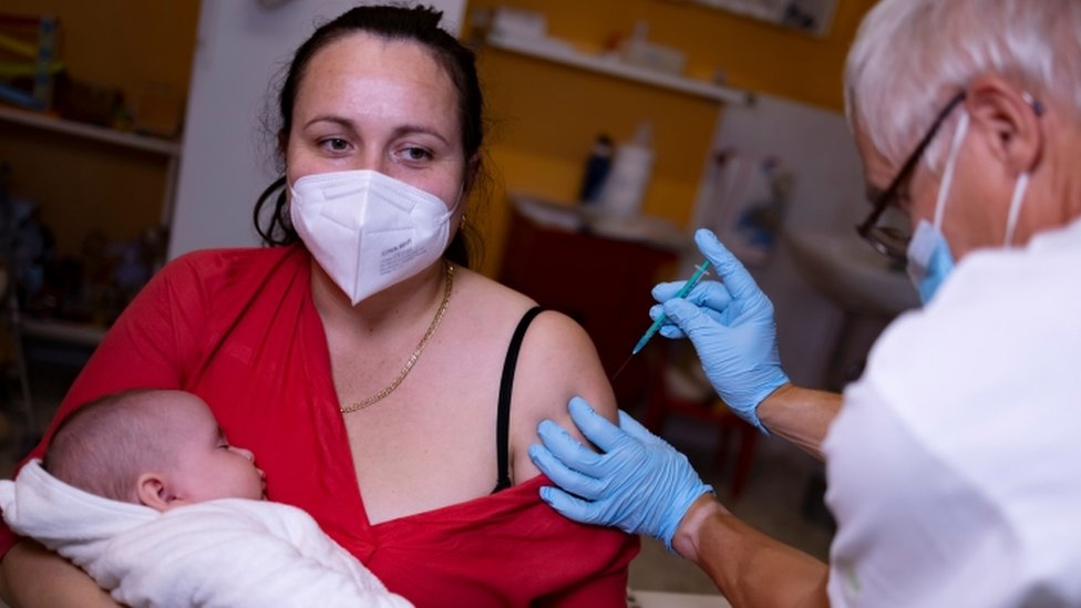 Un médico administra una vacuna contra la enfermedad del coronavirus (COVID-19) a una mujer con un bebé en brazos, en su consulta en Berlín, Alemania, el 2 de noviembre de 2021