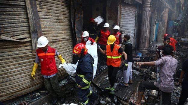 Sukarelawan menyelamatkan sebuah tubuh dari gudang terbakar.