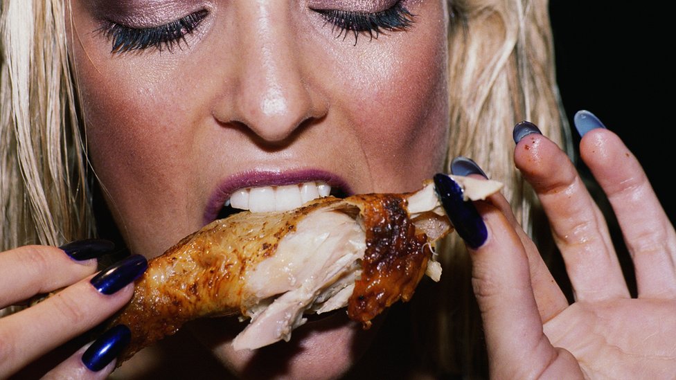 mujer comiendo pollo