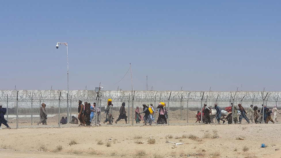 Los afganos caminan entre vallas en la frontera entre Afganistán y Pakistán