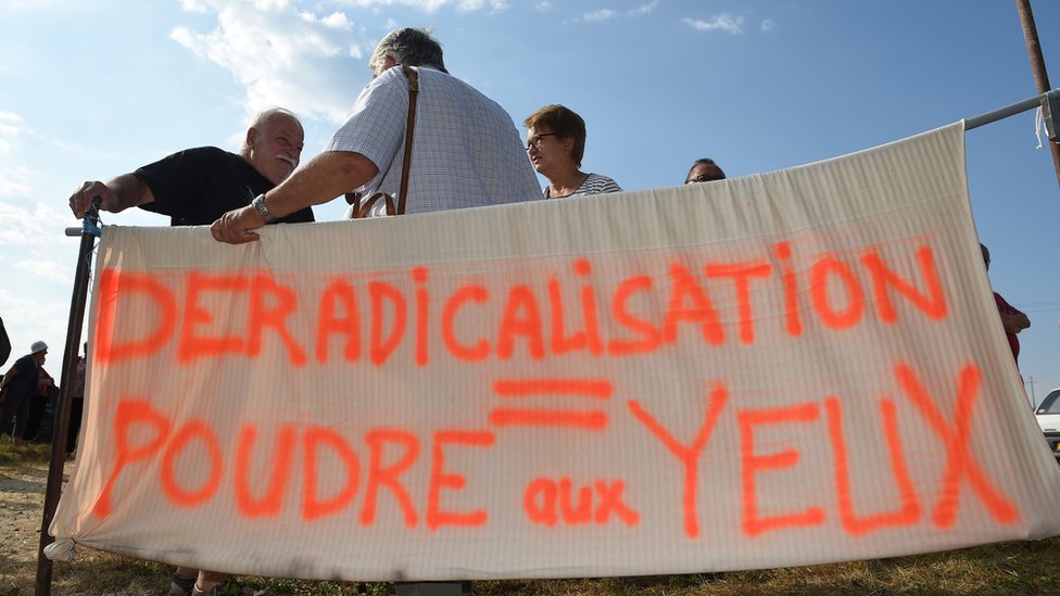 Надпись на баннере: «Дерадикализация = дым и зеркала»