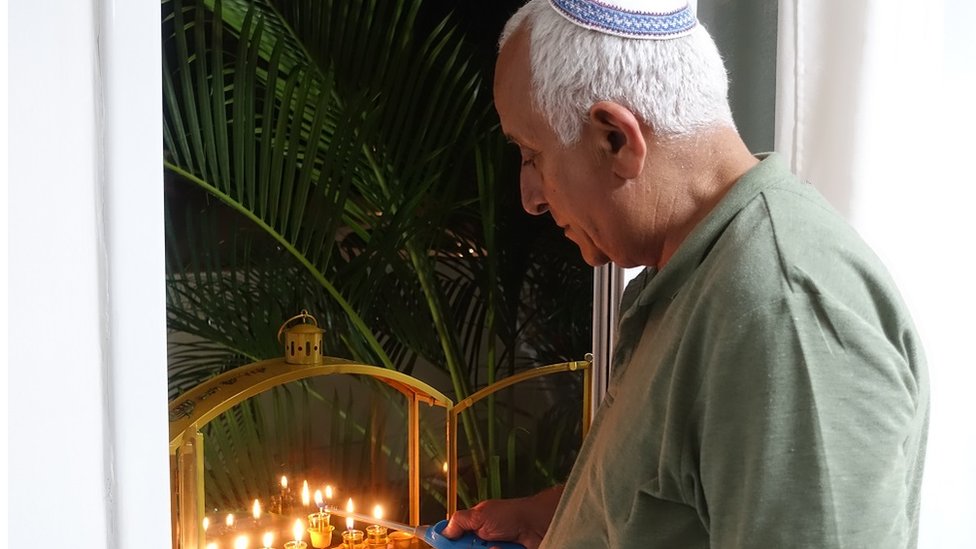 Shai's father Dror looking pensive as he lights candels