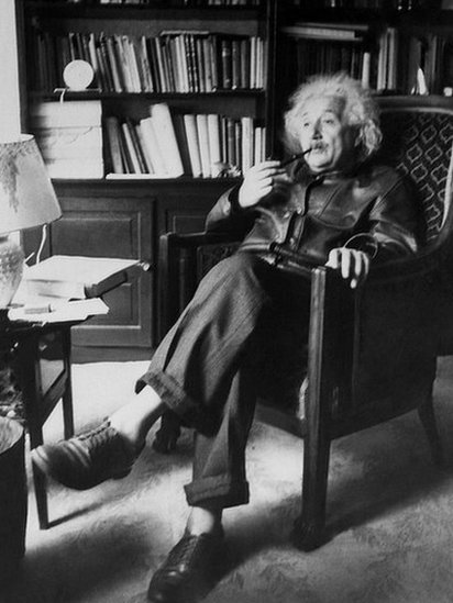 Albert Einstein sentado, fumando y sin medias.
