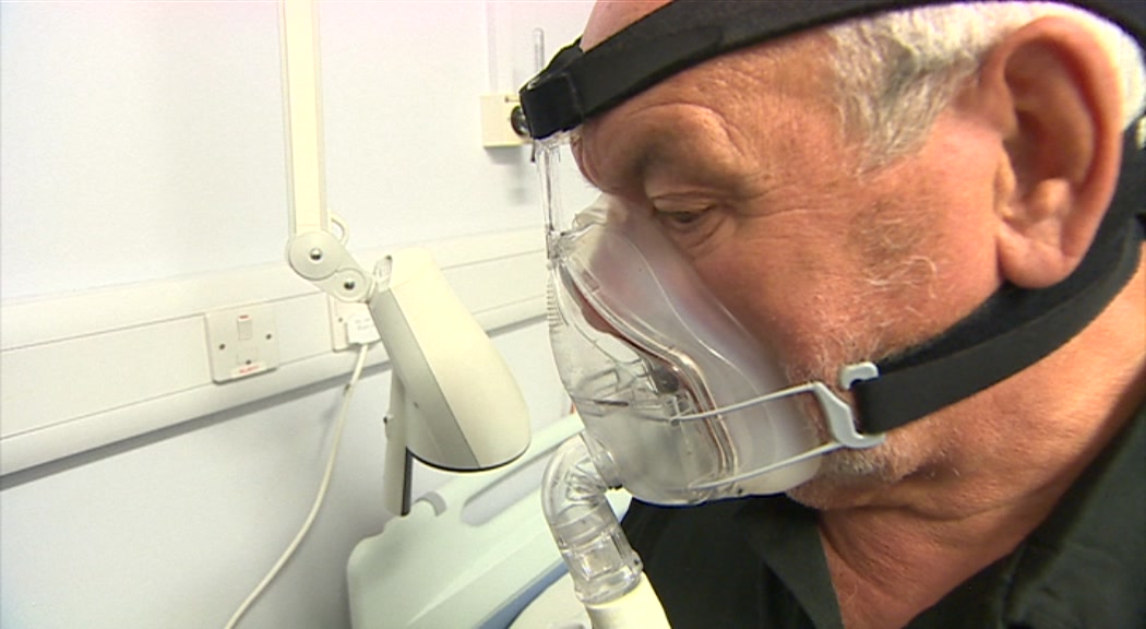 Пациент Майк Морган в маске, которая помогает ему дышать во время сна