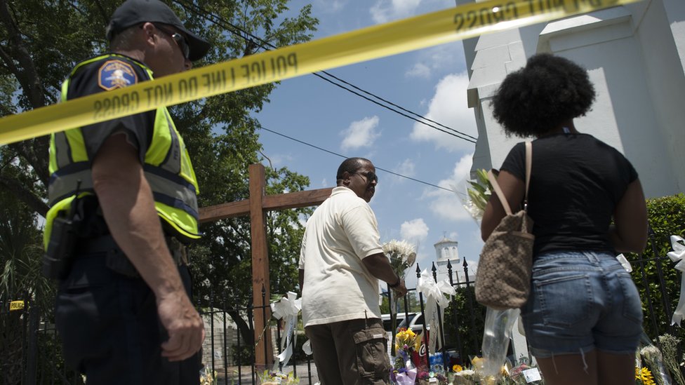 В пятницу люди оставили цветы и послания соболезнования в тылу полиции в церкви Emanuel AME в Чарльстоне, где в среду были убиты девять человек. 2015-06-19.