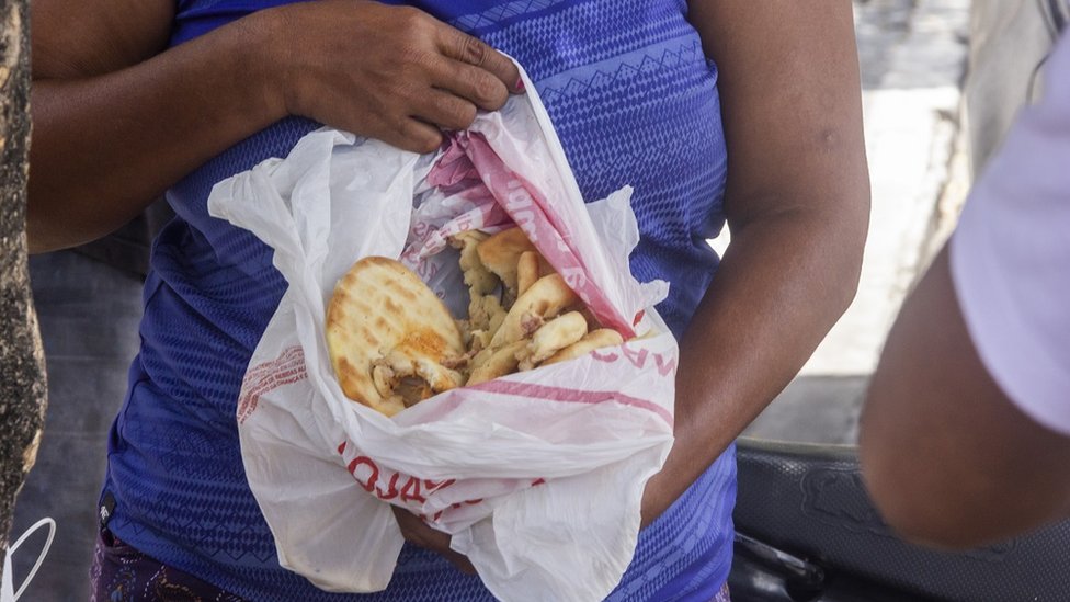 Una mujer muestra unos panes recién encontrados en un camión de basura