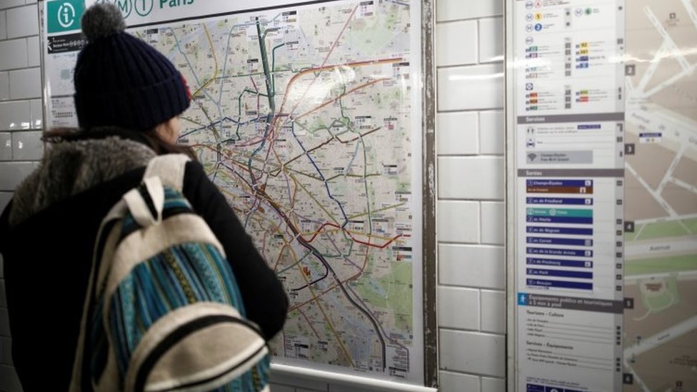 A woman looks at a map of the RATP metro lines at the Charles de Gaulle Etoile metro station