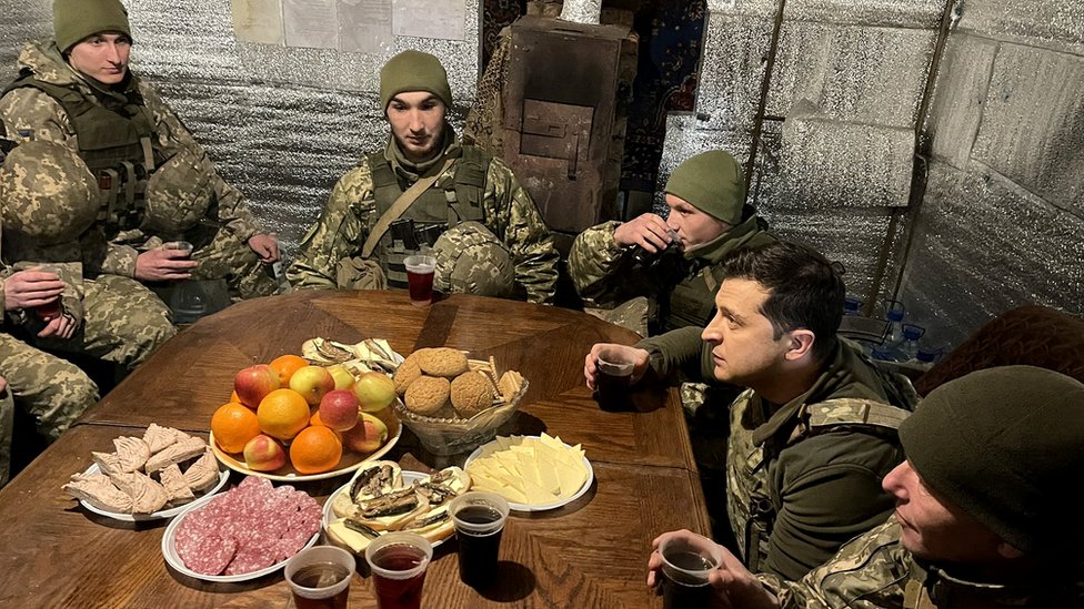 Soldados ucranianos reciben la visita del presidente en el frente del este de Ucrania alrededor de una mesa