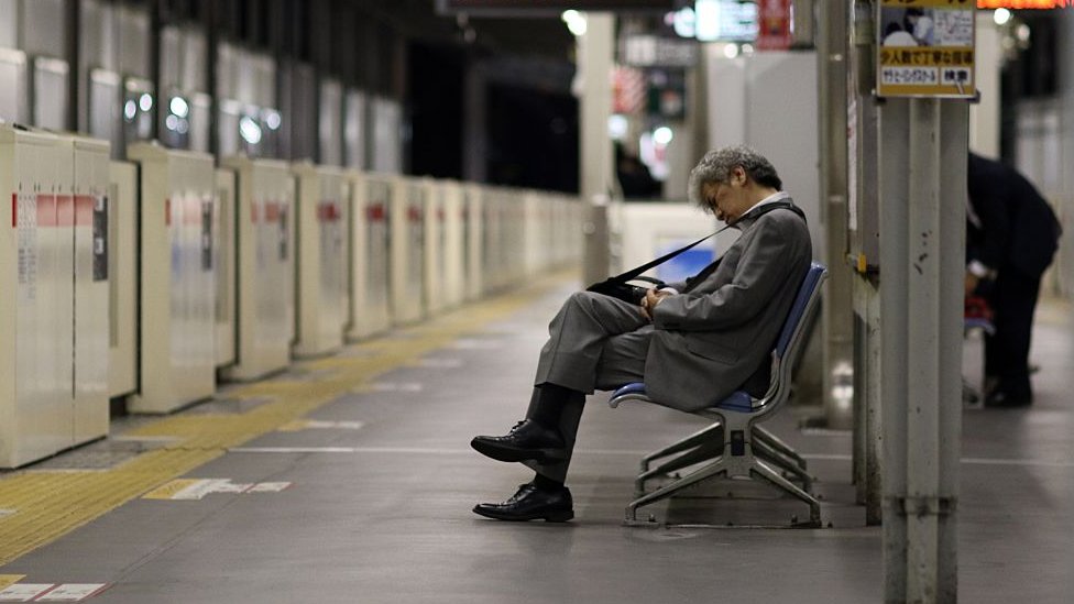 Businessman asleep at a train station in Japan