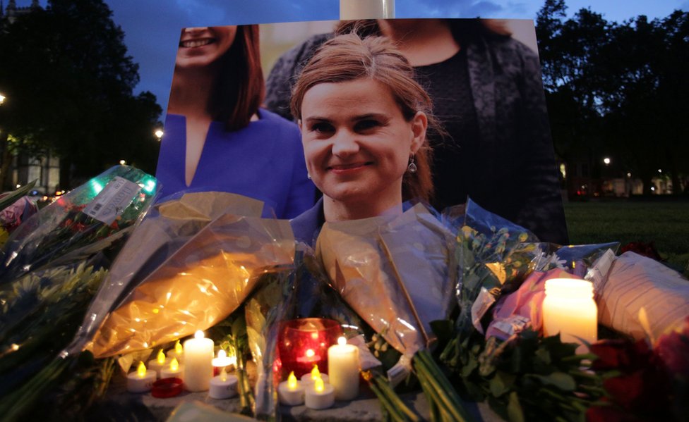 Цветочные дани и свечи помещены рядом с портретом члена парламента от лейбористской партии Джо Кокса на бдении на Парламентской площади в Лондоне