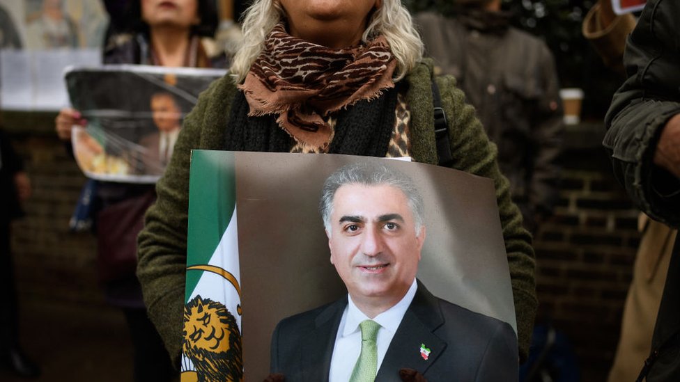 Algunos manifestantes piden el regreso del sha y la monarquía. Manifestante iraní en Londres con u retrato del hijo del último sha.
