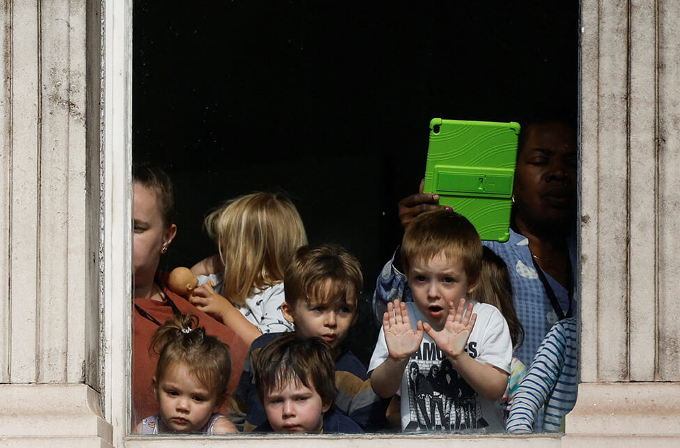 Children peer from a window above Whitehall as the procession passes by