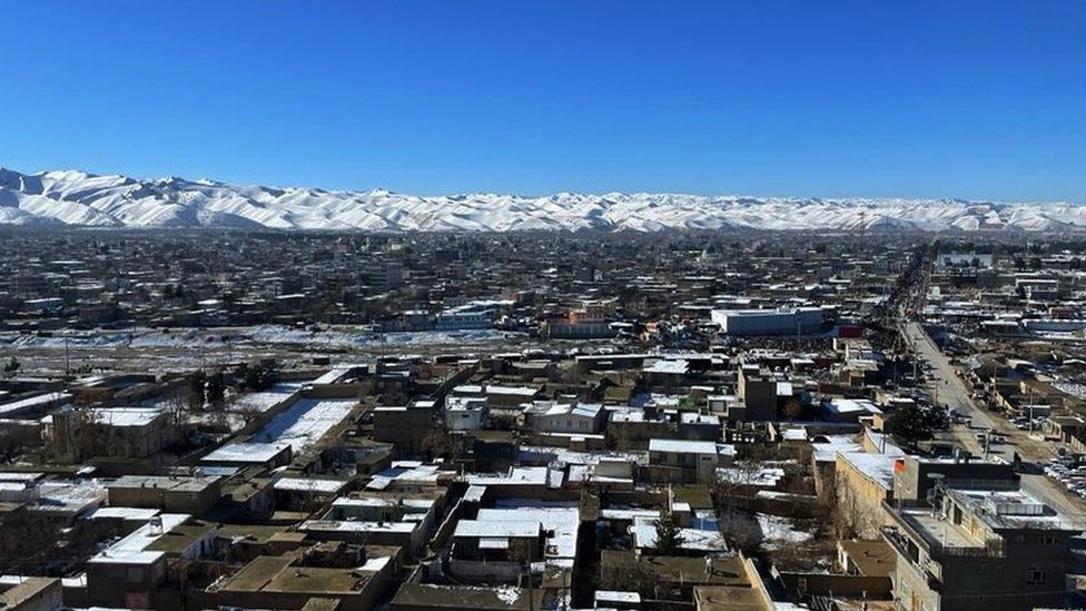 Vista de una pequeña ciudad afgana, con las montañas nevadas de fondo.