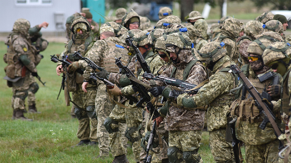 Soldados lado a lado, olhando para armas