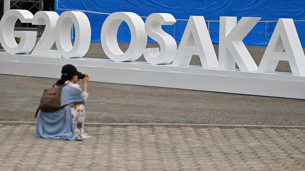 Женщина делает снимок проекта G20 в Осаке, установленного рядом с местом проведения саммита G20 в Осаке 26 июня 2019 года, в преддверии начала саммита позднее на этой неделе.